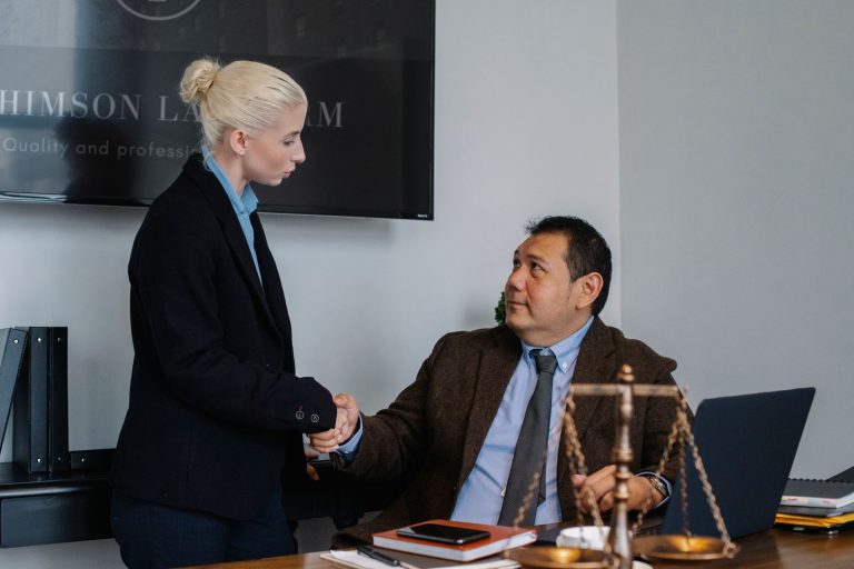 Multiracial coworkers in formal outfit shaking hands near table with scales of justice — A Closer Look at Criminal Law: Steph