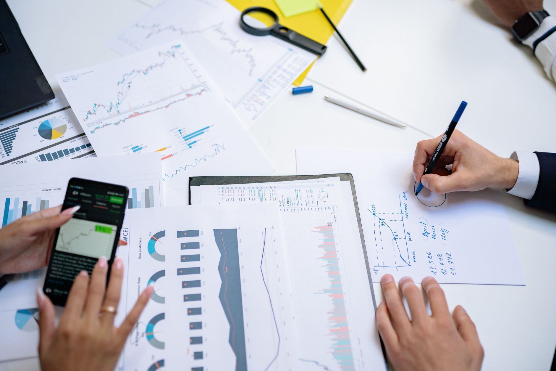 Colleagues collaborating on financial charts and graphs using mobile and paper documents in the office. — Accident with a 18-