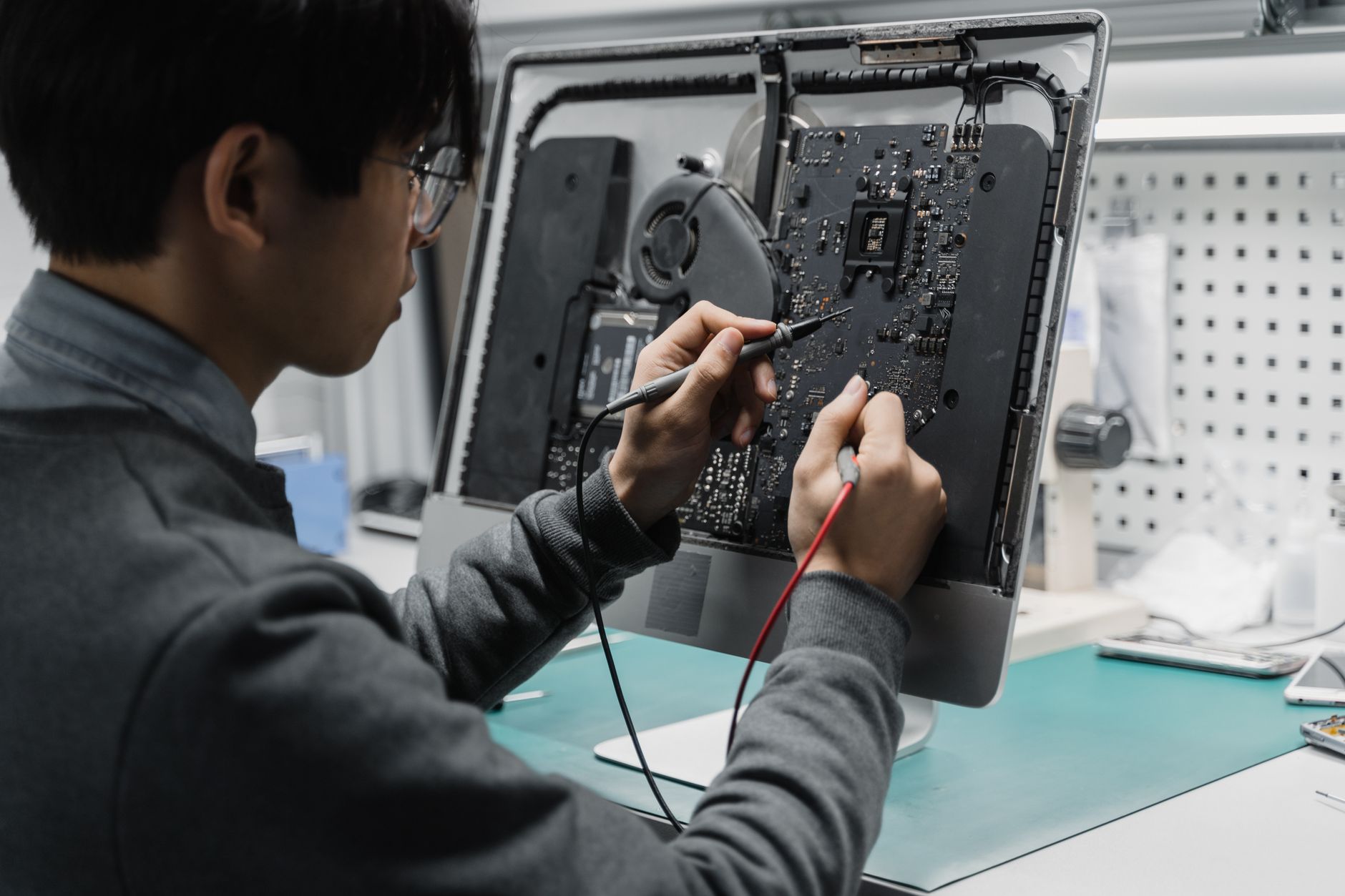 A technician works on a computer motherboard using tools at a workspace, focusing on electronics repair. — Benefits of IPTV :