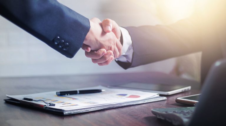 Professional handshake agreement over business charts in an office setting. — Cannabis drink options and how these beverages