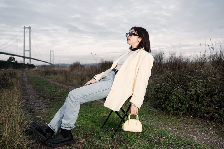 A stylish woman in sunglasses relaxes on a chair by a bridge in nature. — Comment maximiser son plaisir au blackjack sur Sims