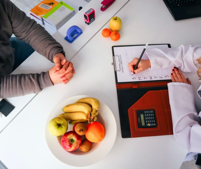 Top view of a dietitian planning a healthy diet with fresh fruits on the table, focusing on health and nutrition. — Dr. Wende