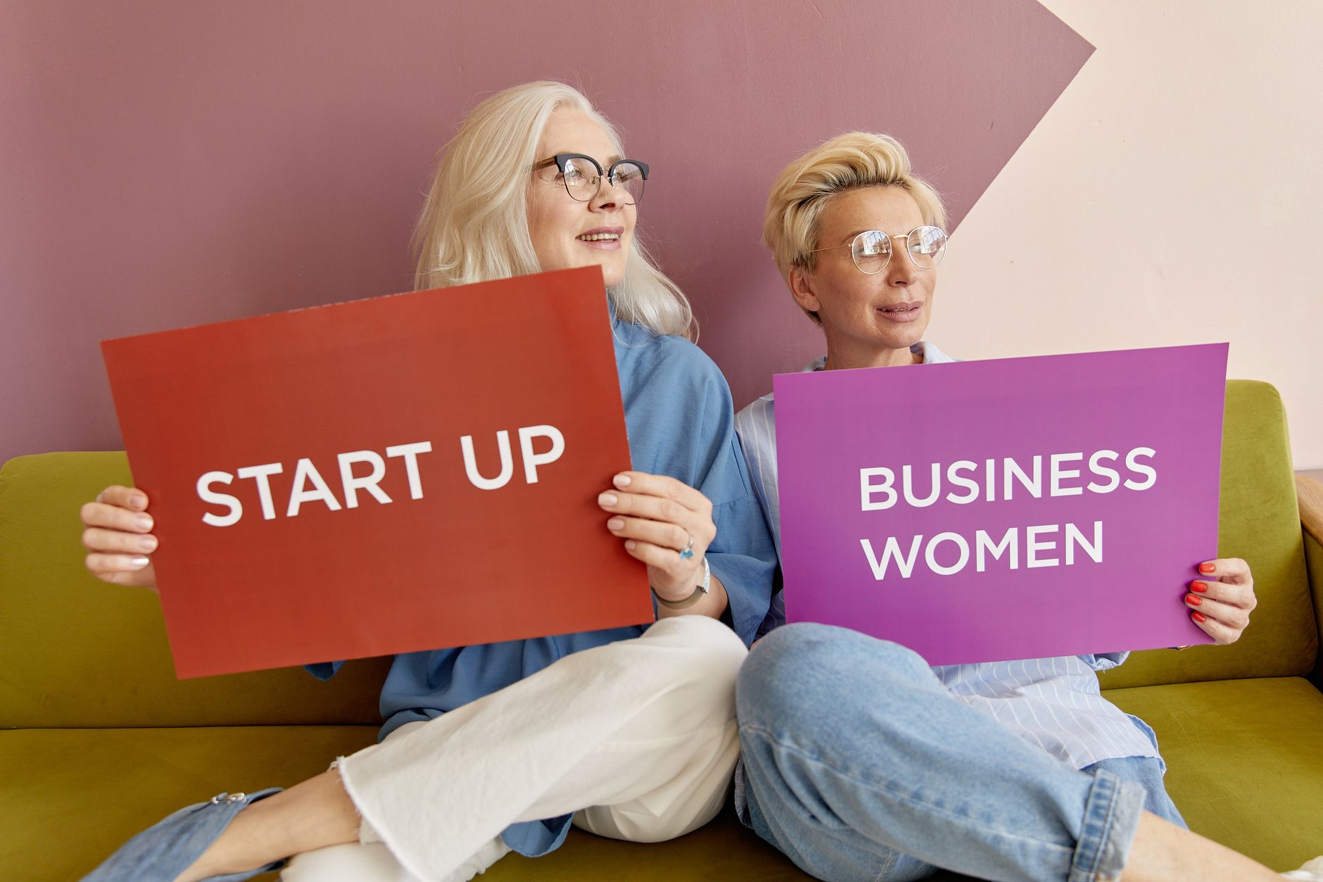 Two women on a sofa holding signs promoting startup and business women. — Elevating Event Marketing with the Magic of 360 Pho
