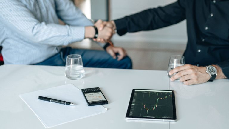 Business meeting with handshake and financial analysis displayed on a tablet. — Enjoy Tailored Services From Toronto Escorts