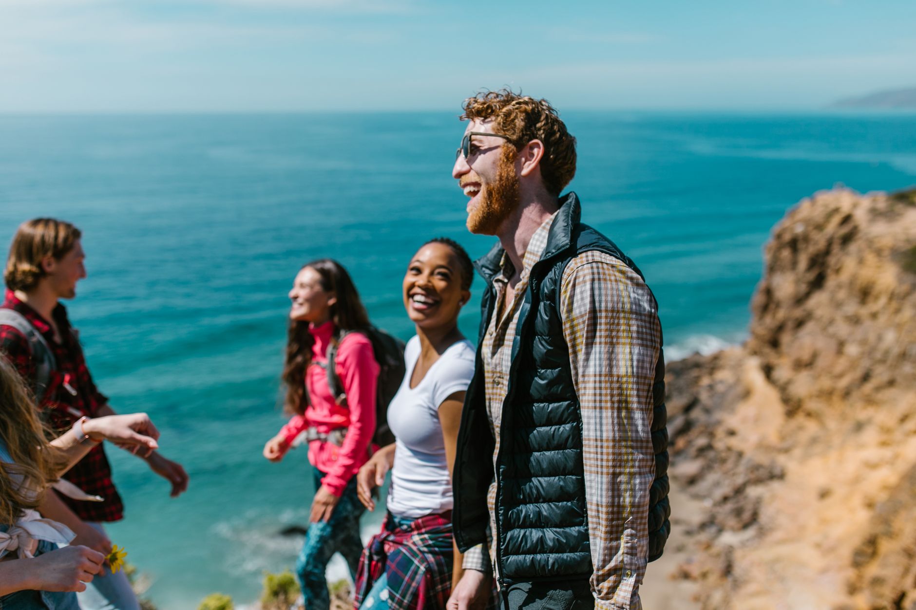 A joyful group of friends hiking along a scenic coastline, enjoying laughter and good company. — Entertainment City: Offering