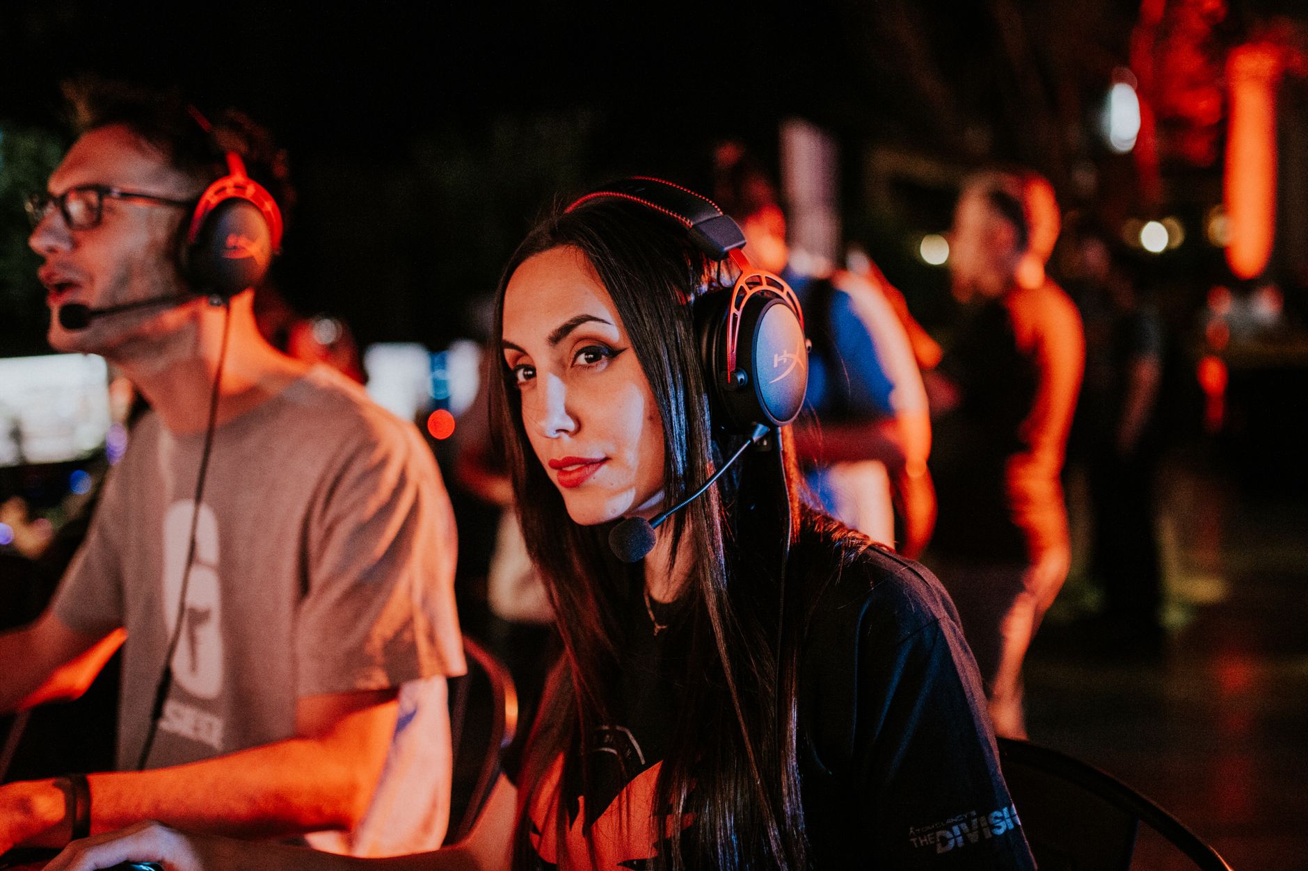 Woman gaming in esports tournament, wearing headset with focused expression, dimmed indoor lighting. — Experience Fair Play a
