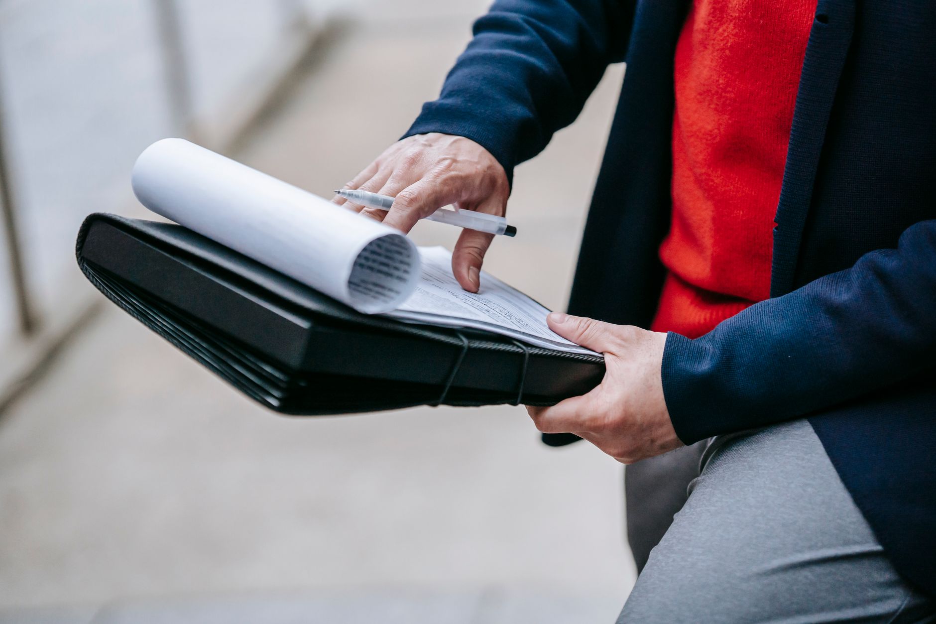 Close-up of a professional person reviewing documents outdoors. Engaged in work with focus on writing materials. — Experience
