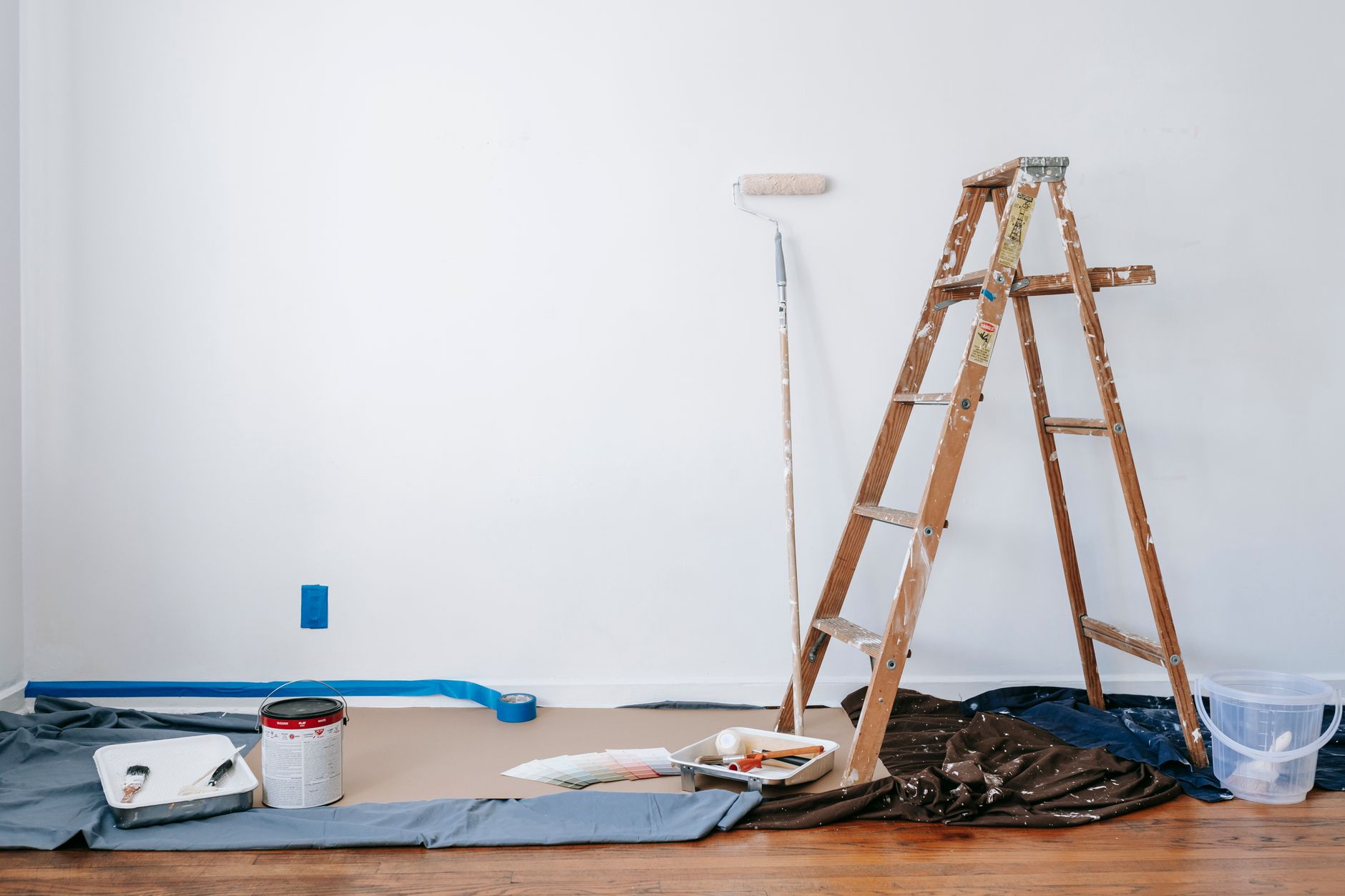 A room prepared for renovation with a ladder, paint supplies, and drop cloth. — How To Create A Lowes Vinyl Flooring That Is