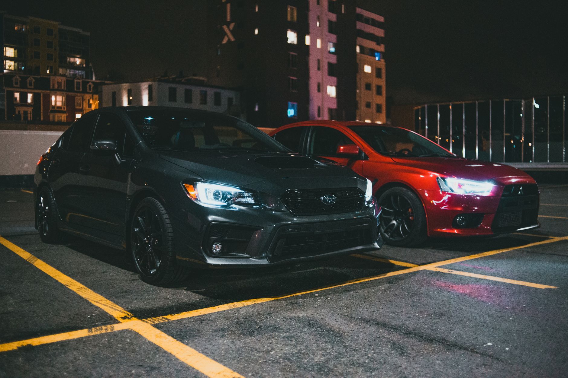 Two sports cars parked in a city parking area at night, showcasing urban nightlife vibes. — How To Get Into Fast Traffic Safe