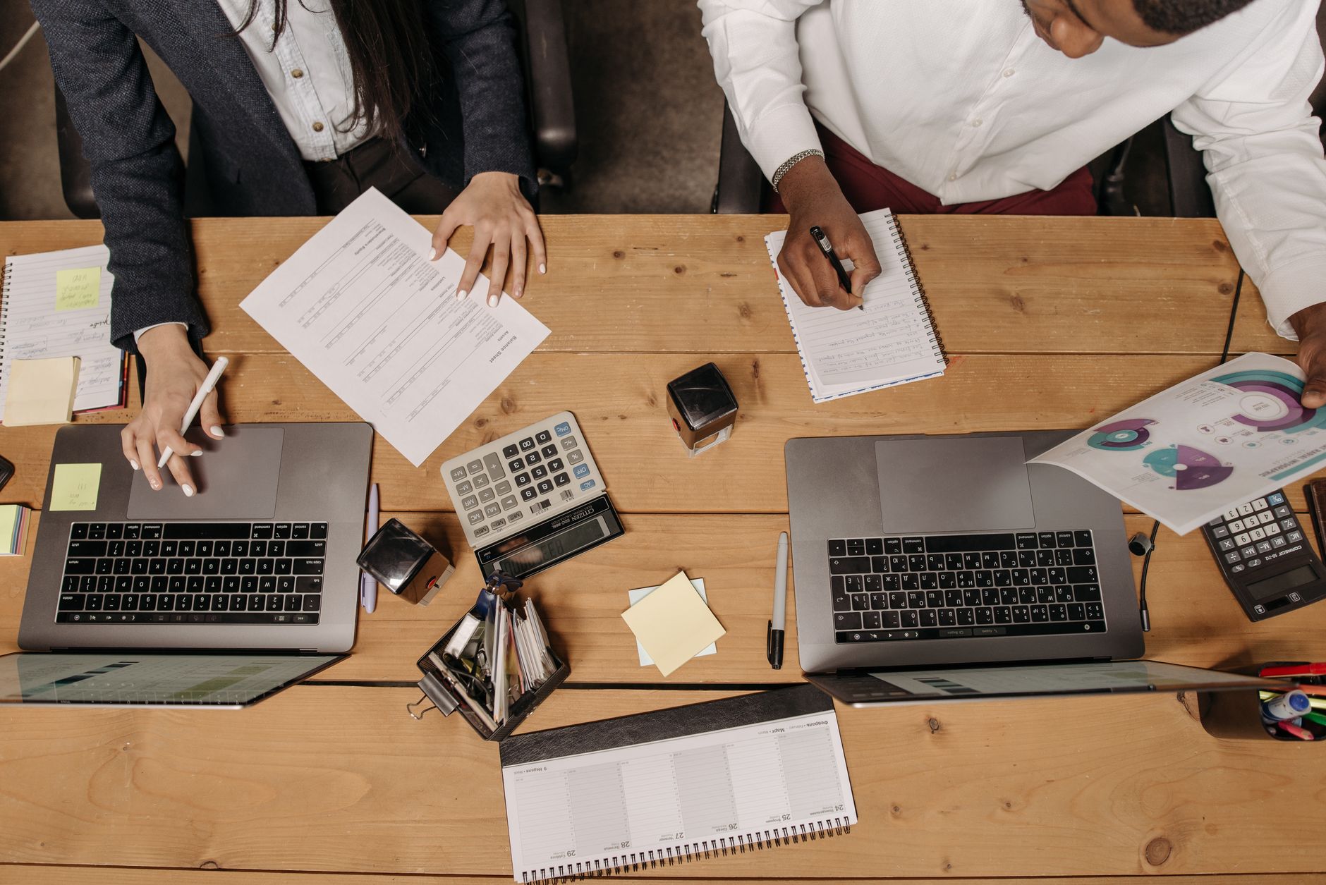 High-angle view of professionals working collaboratively with laptops and documents in an office. — How to Optimise Your Webs