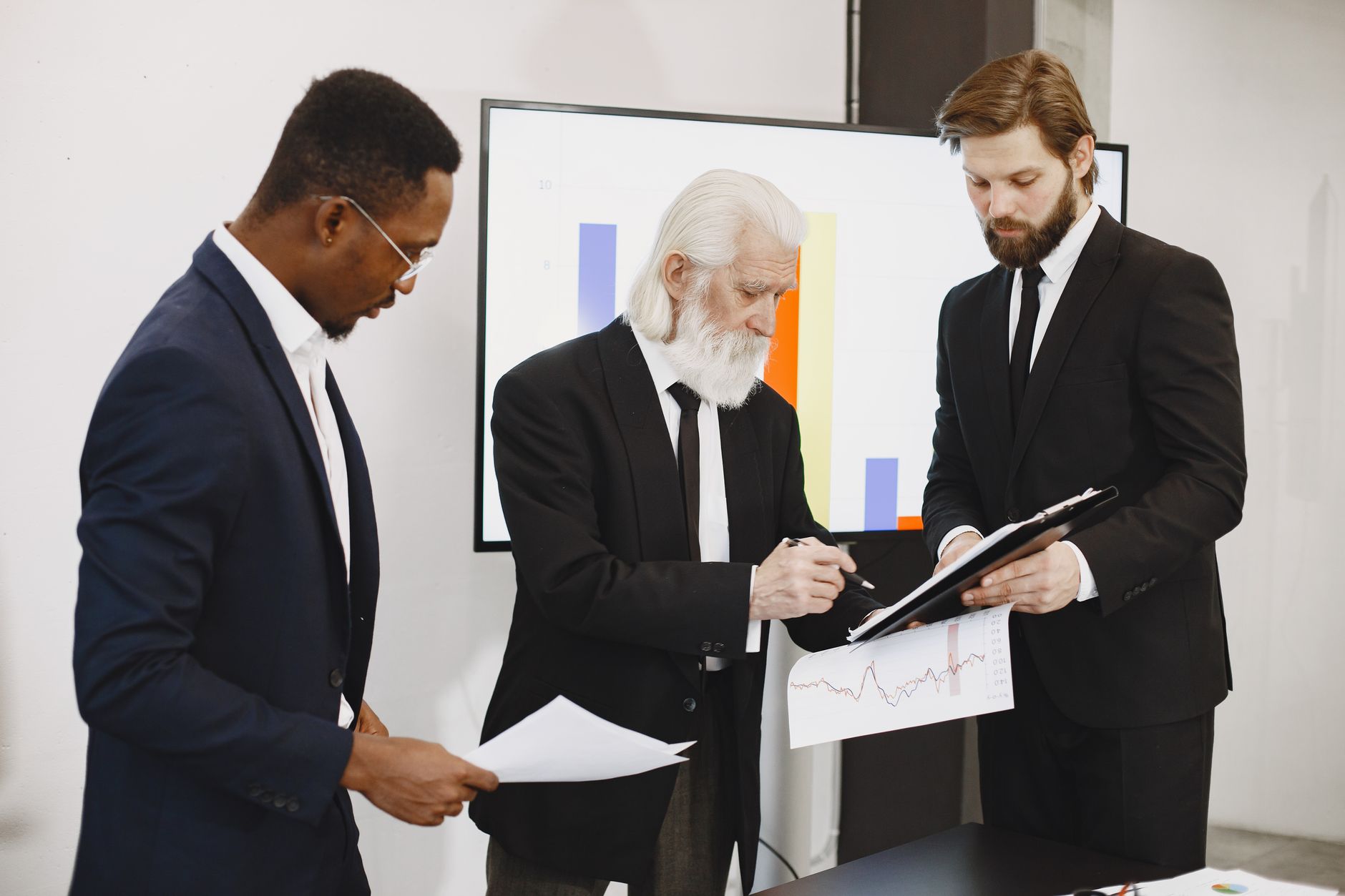Three businessmen in suits reviewing reports and graphs during an office meeting. — Introduction to Ostarine and Its Benefits