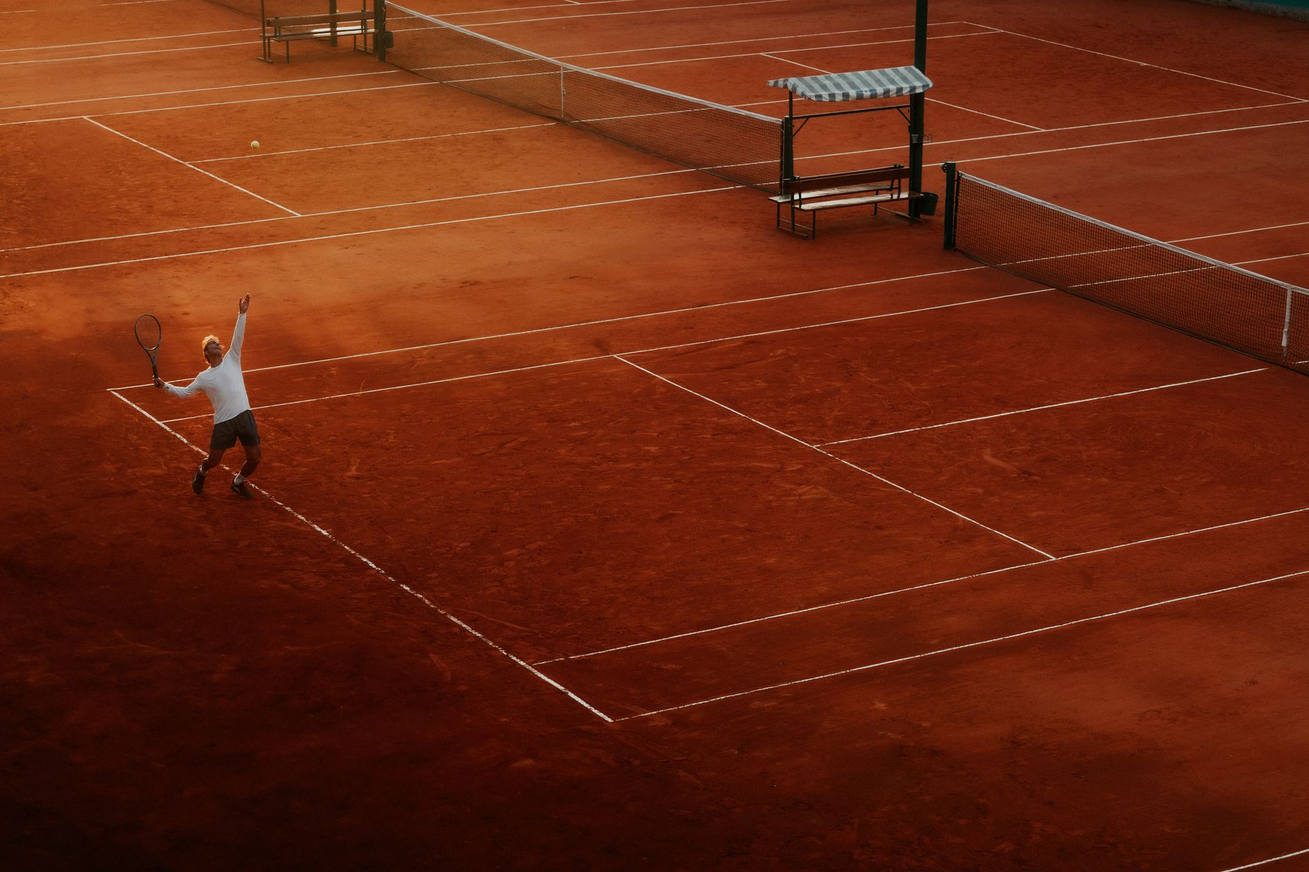 A player serves on a clay tennis court, highlighting the beauty and intensity of the sport at sunset. — Latest Updates On Spo
