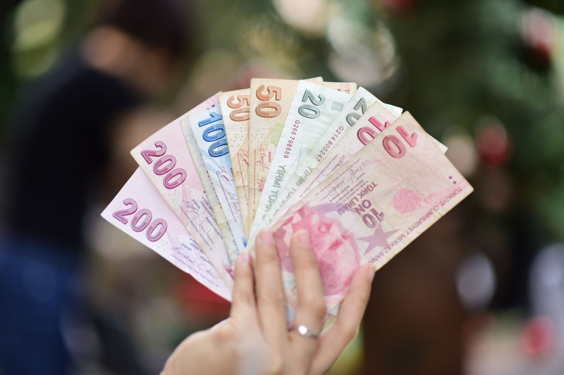 Hand holding multiple denominations of Turkish Lira banknotes outdoors. — NV Casino choix des fournisseurs et nouveautés 2024