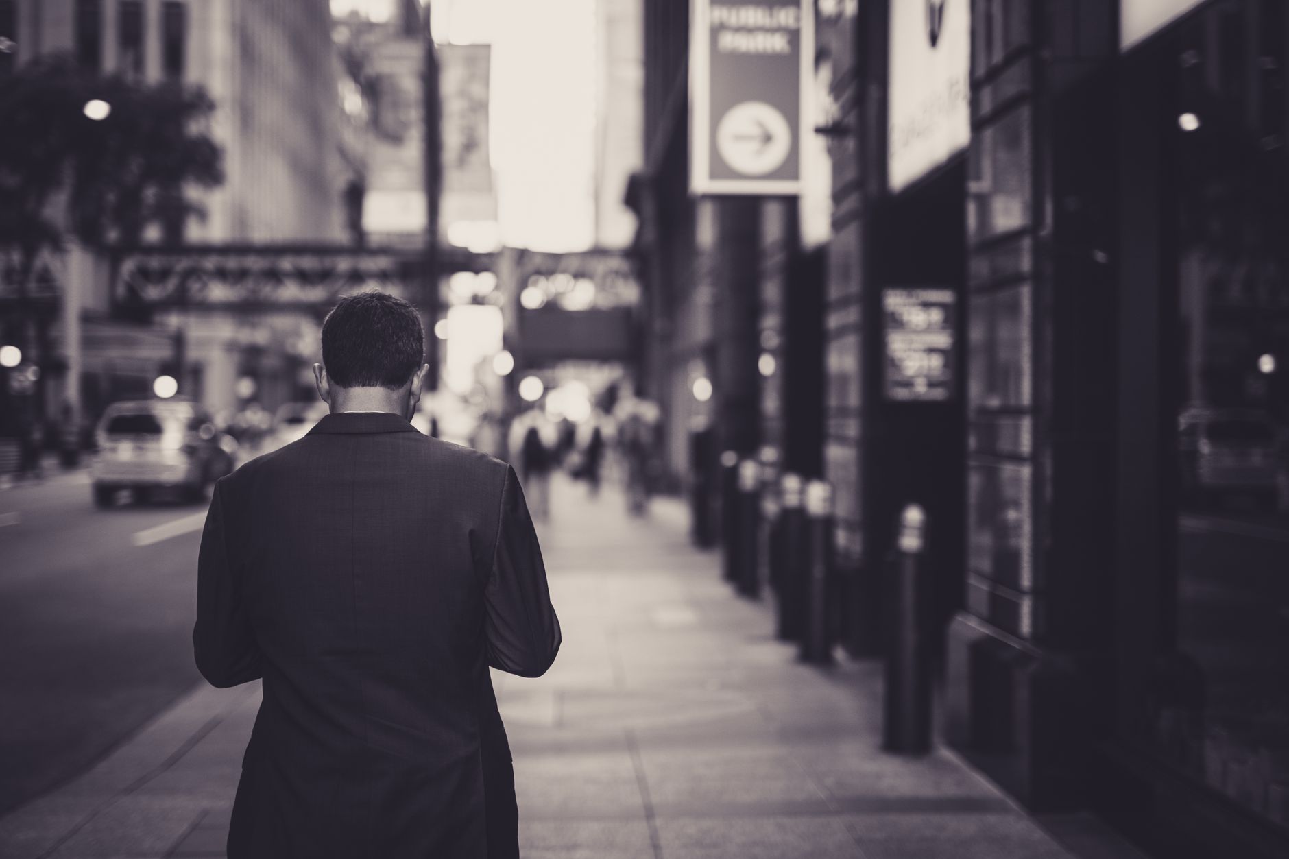 Man in a suit walking down a city street in a lonely, urban setting. — Strengthening the Economy: The Ripple Effect of New Jo