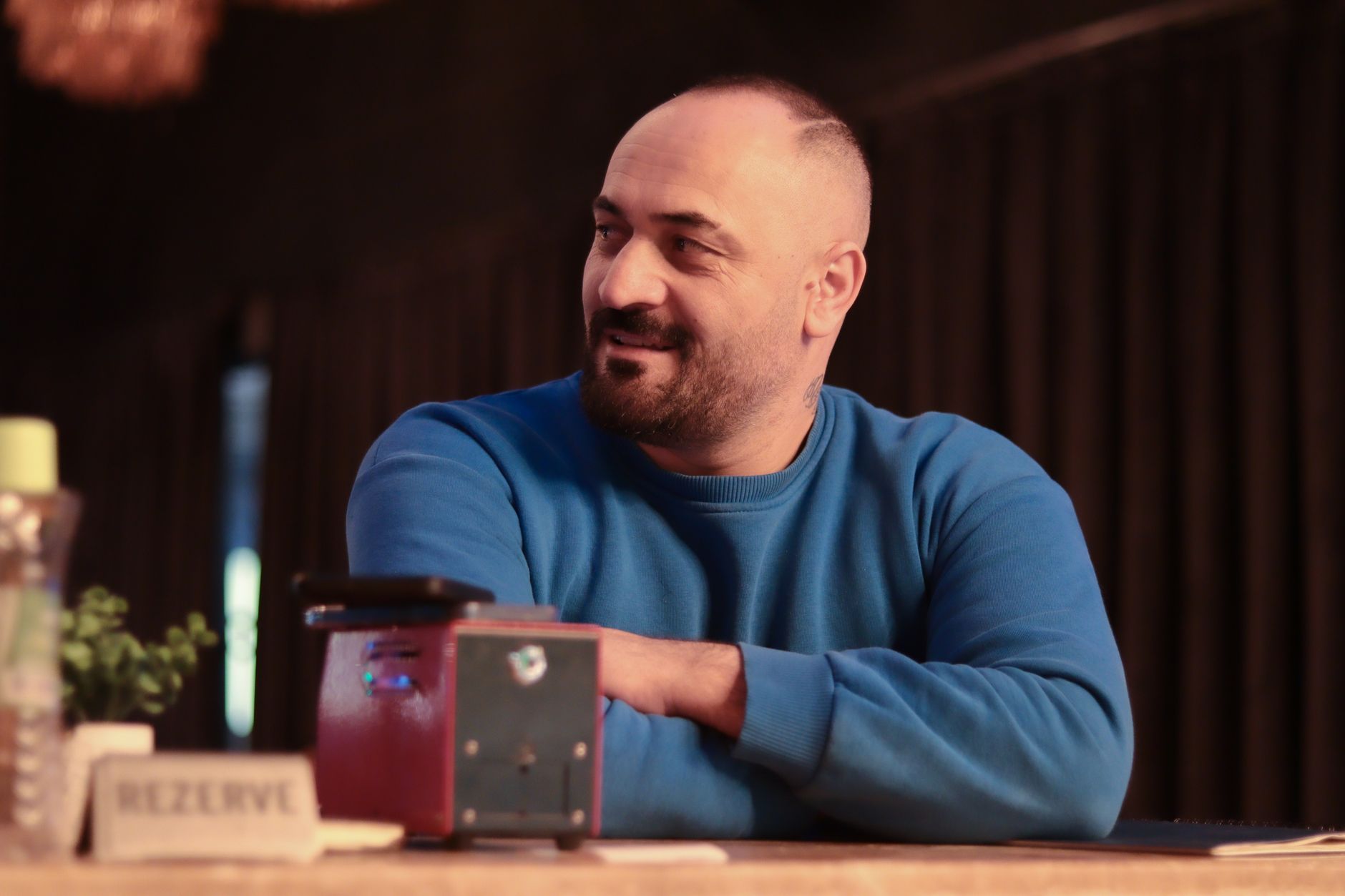Casual portrait of a man in a blue sweater sitting indoors at a restaurant. — A Guide to Buyer Safety When Purchasing