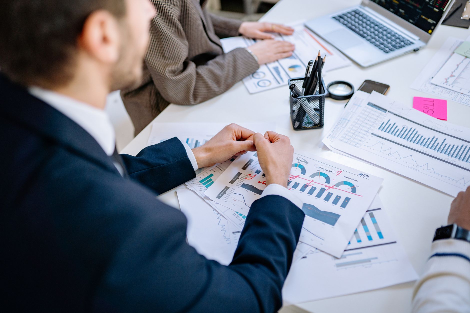 Business team analyzing financial graphs at a meeting table, fostering collaboration in an office environment. — Bene