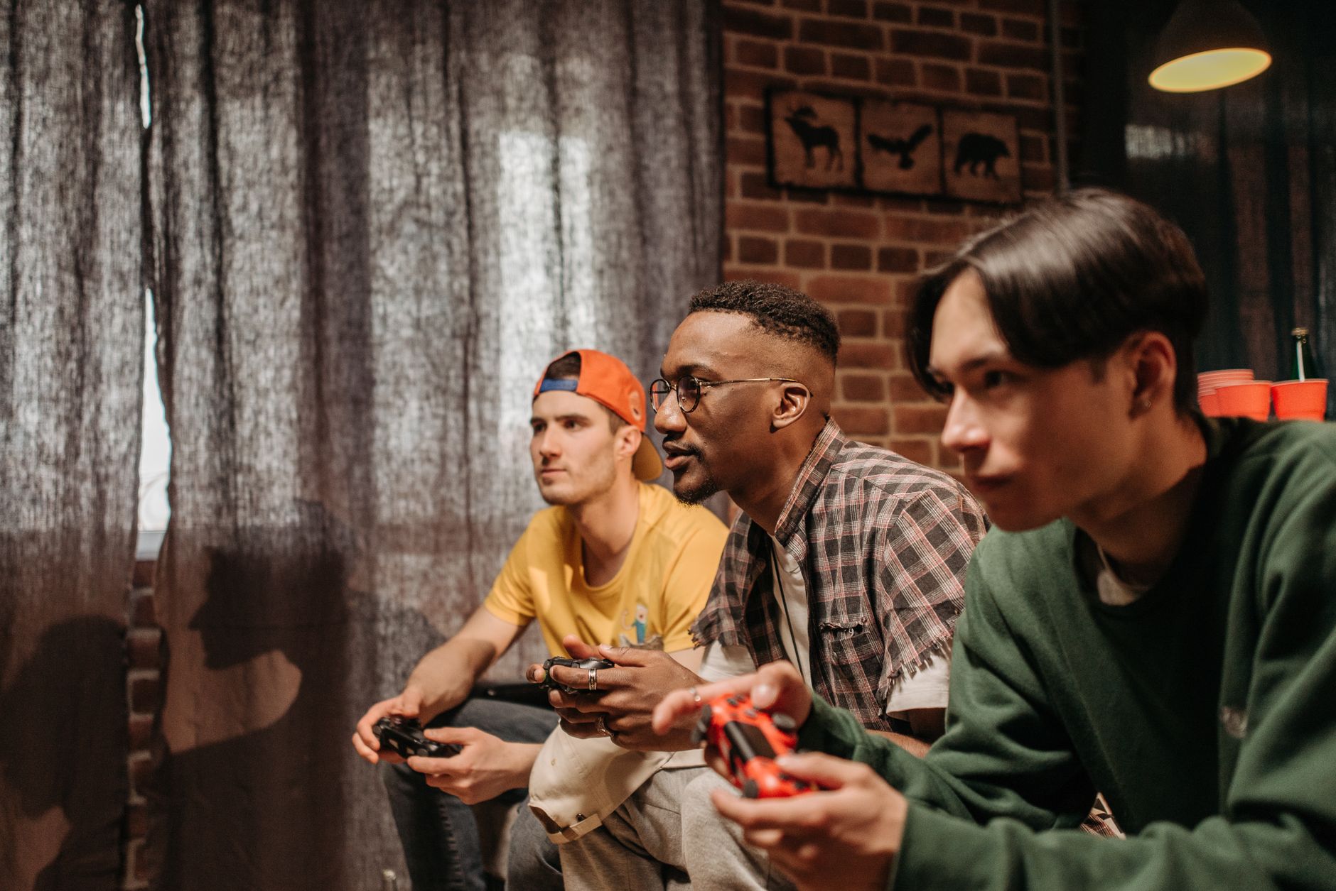 Three men focused on playing video games with controllers indoors. — Get Familiar With The Rules And Strategies Of Di