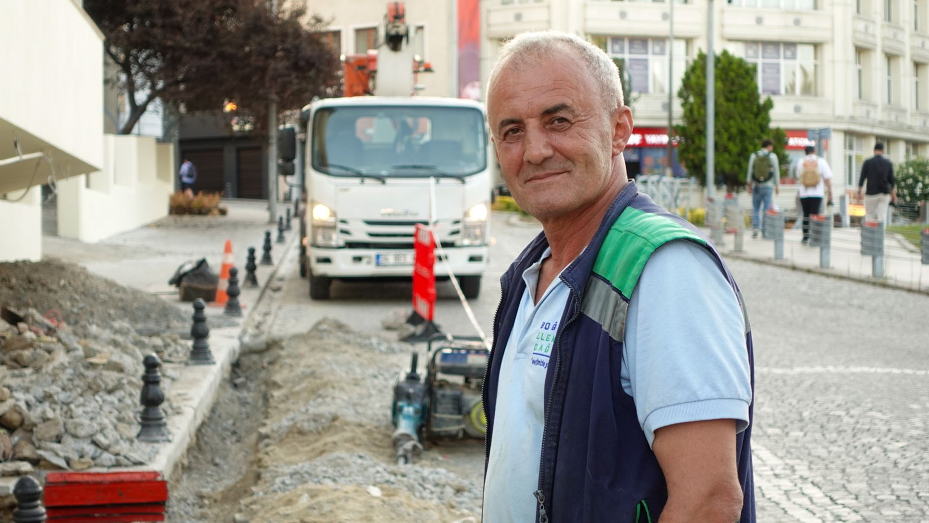 Smiling construction worker on a city street with vehicles and buildings. — Get Real YouTube Subscribers Without Brea