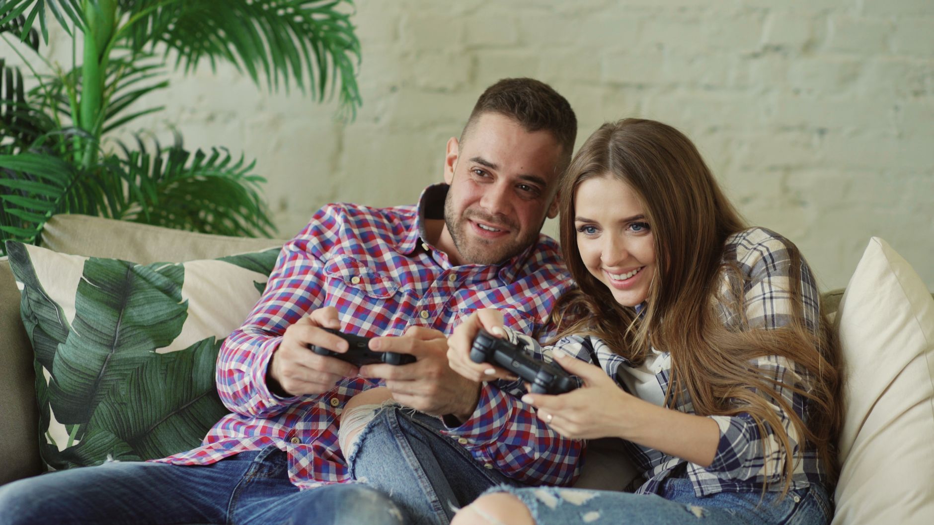 Happy couple enjoying video games together at home on a cozy sofa. — How to Make Profitable Bets on UFABET Football