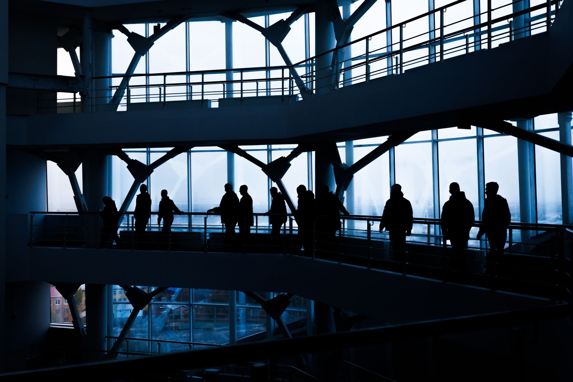 Silhouettes of people walking in a modern architectural building with large windows. — What You Need to Know About Fa