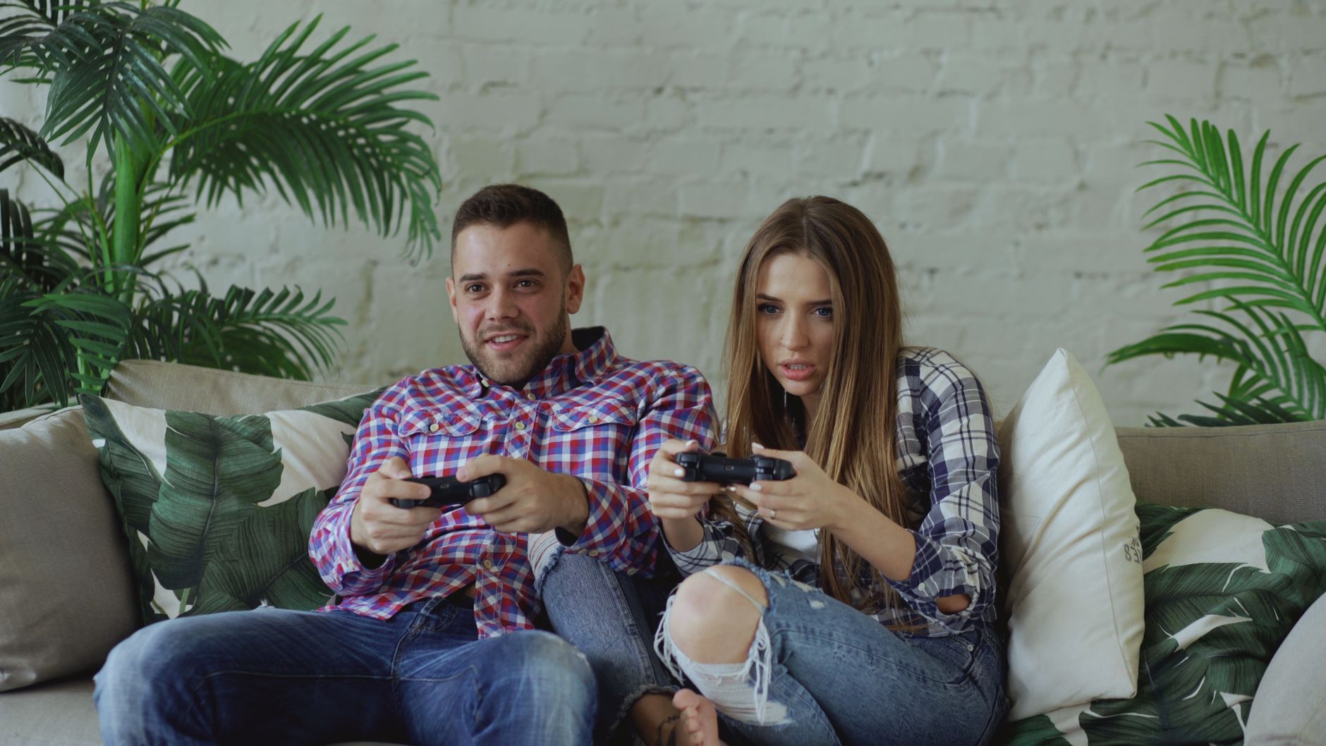 Young couple playing video games intensely on a couch, enjoying leisure time indoors. — Take A Chance On The Wildest Slots Ar
