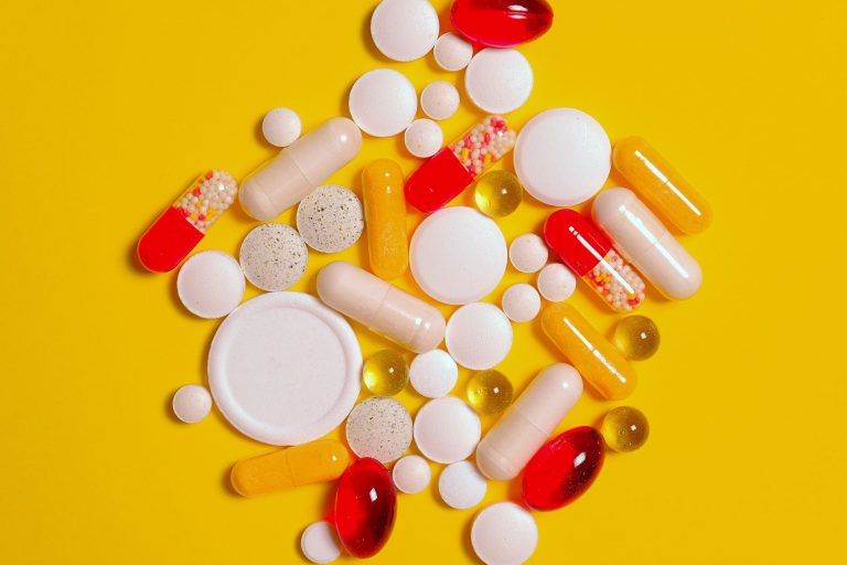 A vibrant assortment of pills and capsules on a bright yellow background, ideal for healthcare themes. — The Accessibility of