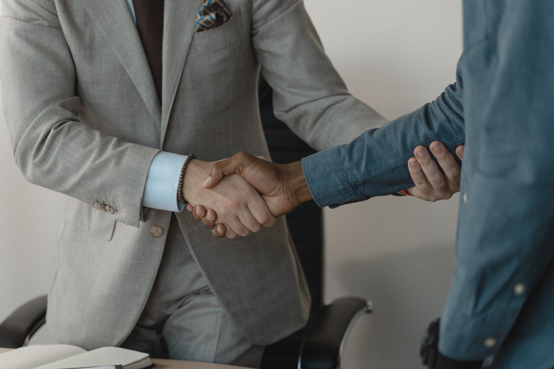 Image of a professional handshake between two businessmen in an office setting. — The Aesthetic Value of Teller Windows in Co