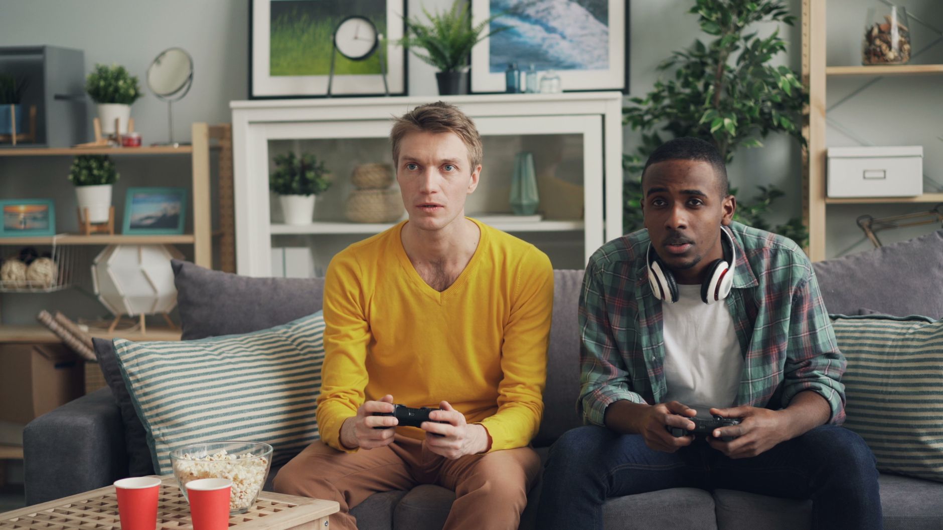 Two friends focus on gaming while relaxing on a couch in a modern living room. — The Therapeutic Benefits of CBD: How Cannabi