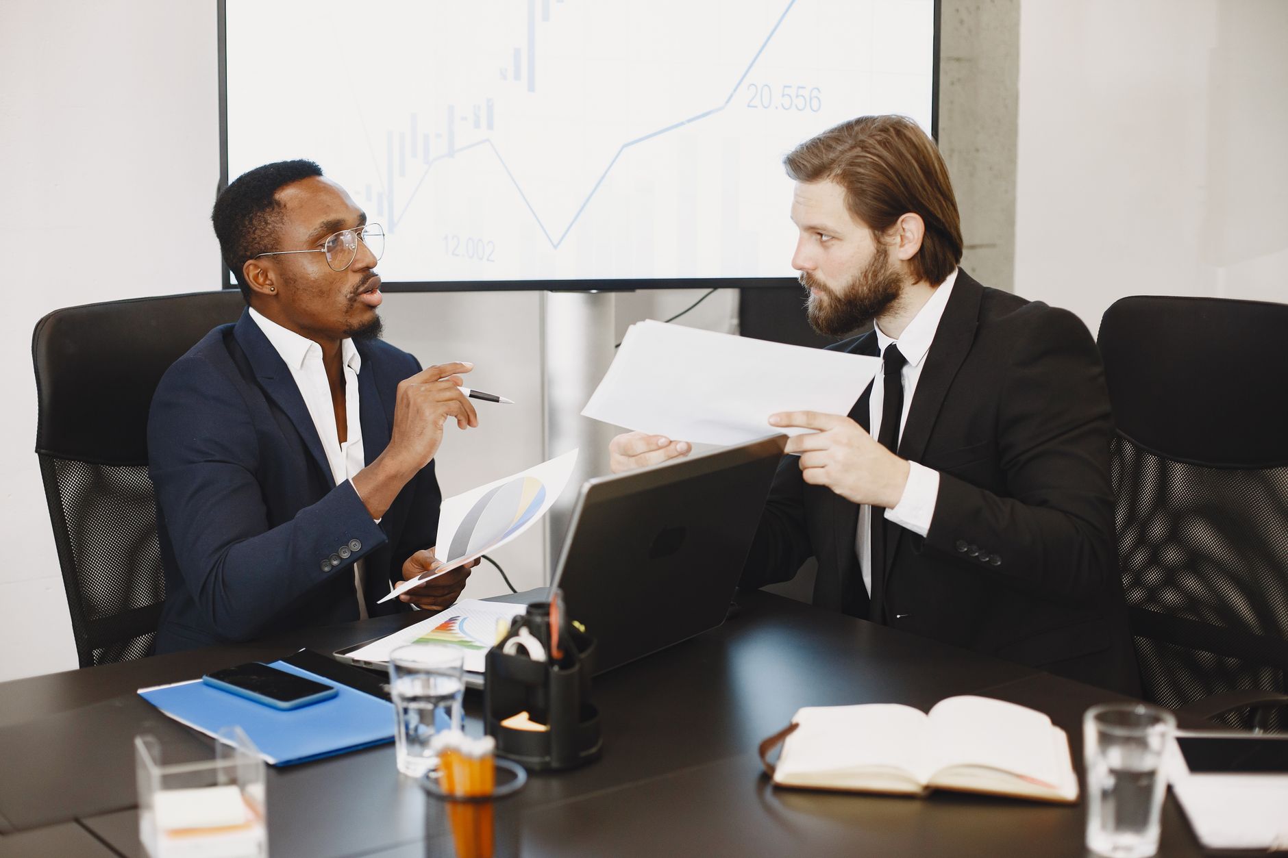 Two business professionals engaged in a planning meeting, discussing documents in a modern office setting. — Tips on Forex Tr