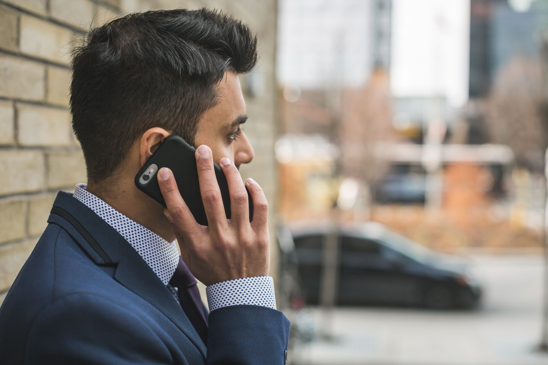 Professional man in suit making a phone call outside in city setting. — Tips on how to buy Instagram followers