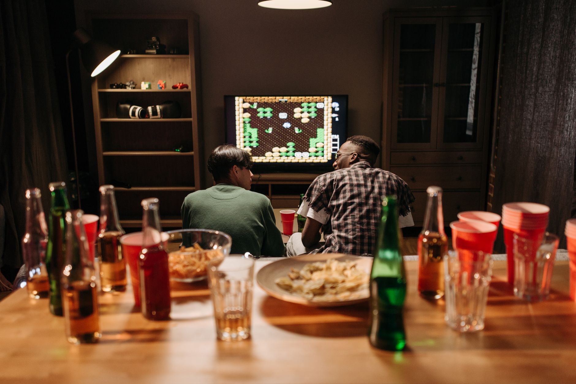 Two friends enjoy a video game night surrounded by drinks and snacks. — Top tips for managing your money at online casinos
