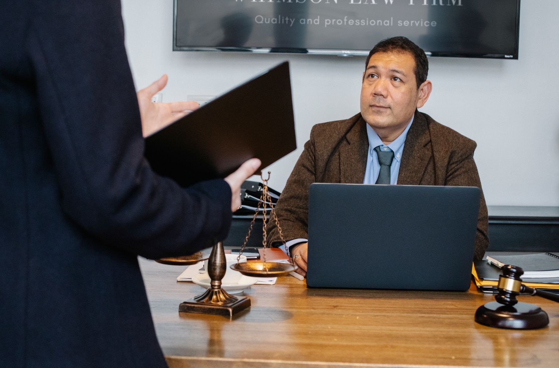 Crop unrecognizable employee representing new case details to concentrated middle aged ethnic lawyer sitting at table with la