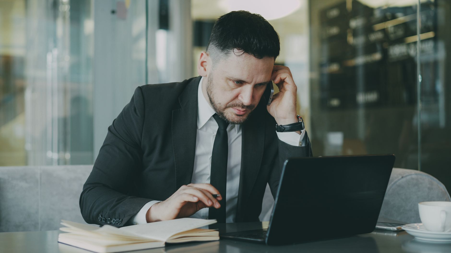 Focused businessman in suit multitasking on phone and laptop in modern office. — Ways to Increase Your Marketing Results with