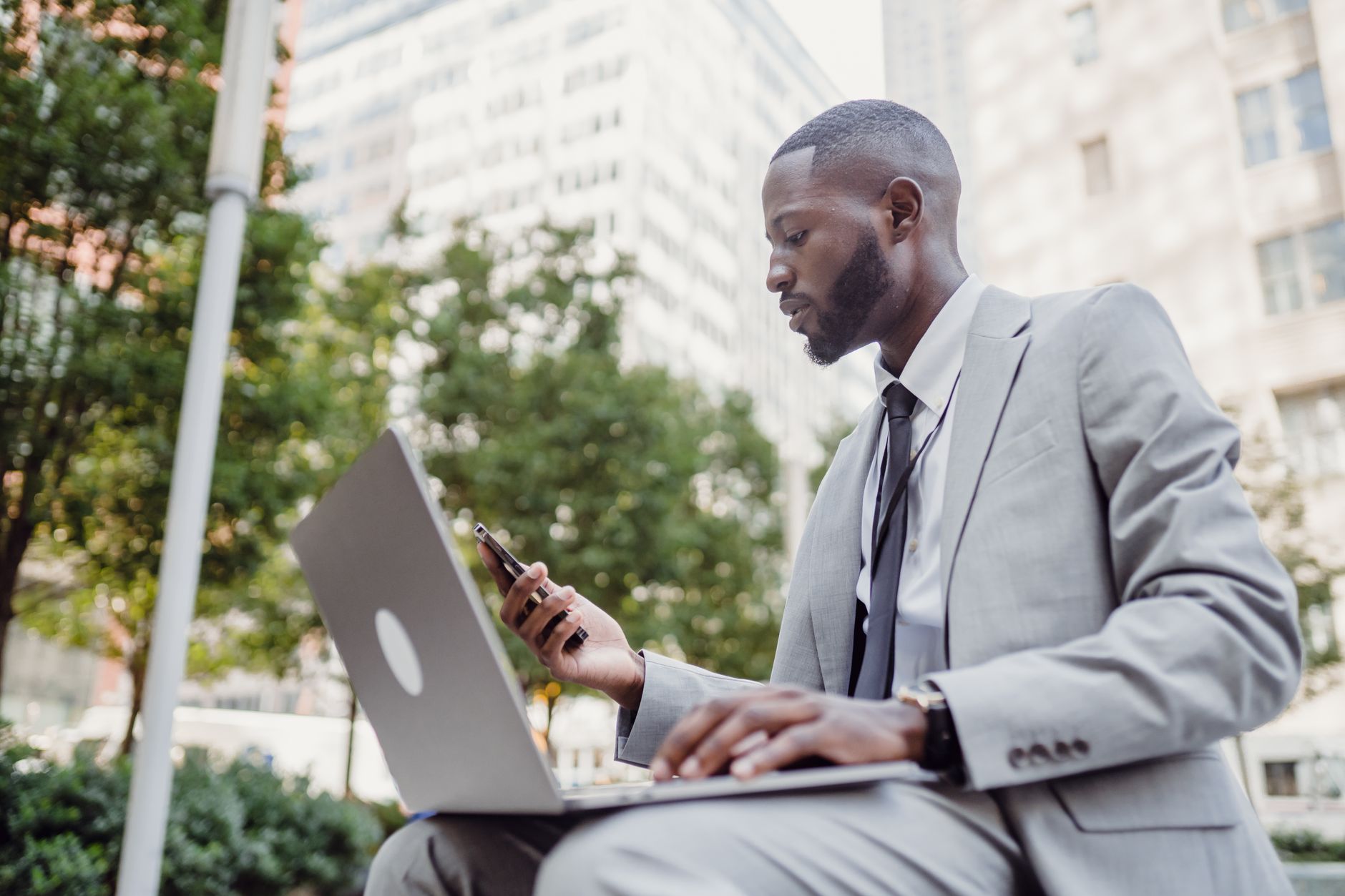 Businessman in a suit using a laptop and smartphone in an urban setting, blending technology with business. — What to Look fo