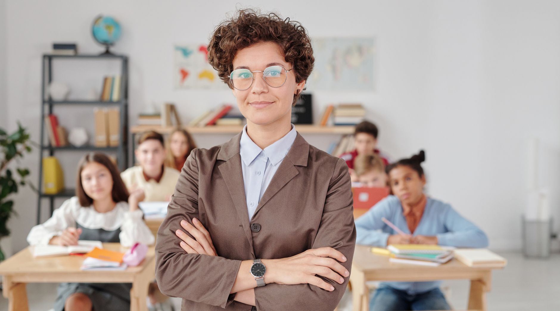 A confident teacher stands in front of students in a classroom setting. — Why do parents need to consider an online tutor?