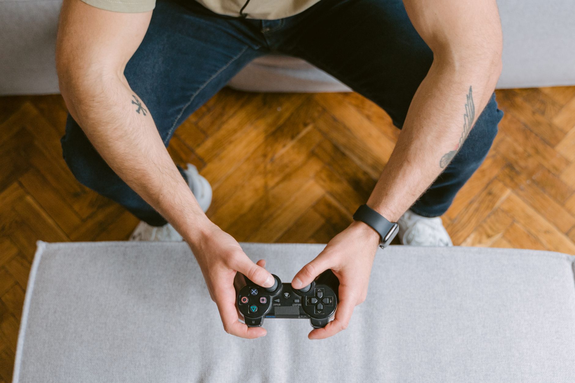 A man sitting on a couch holds a game controller, ready to play video games. — Why should you consider pgslot to earn massive